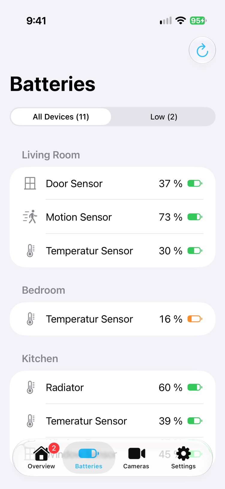 The Batteries tab. A filter switches between all 11 devices and the 2 with a low battery. Devices are grouped by room, each with its battery level and a battery symbol.